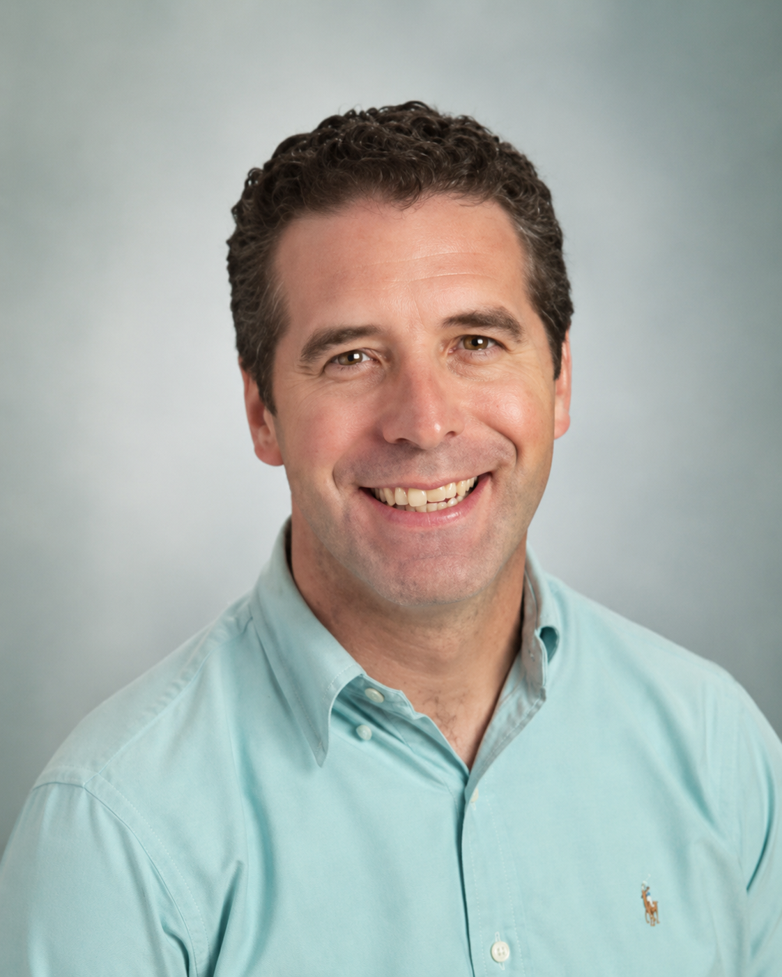 Daniel Patrick Griffin, President of EnrollmentCoach, smiling in a light blue shirt